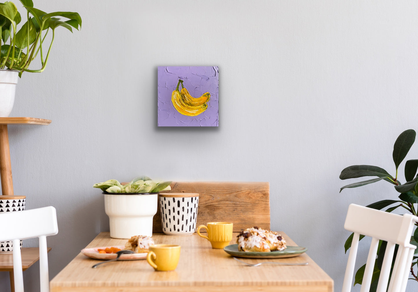 Dining area with a table set for breakfast, plants, and a wall art piece.