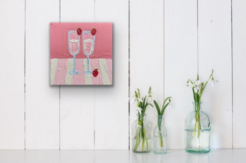Painting of two champagne glasses with cherries on a pink background, displayed on a white wall.