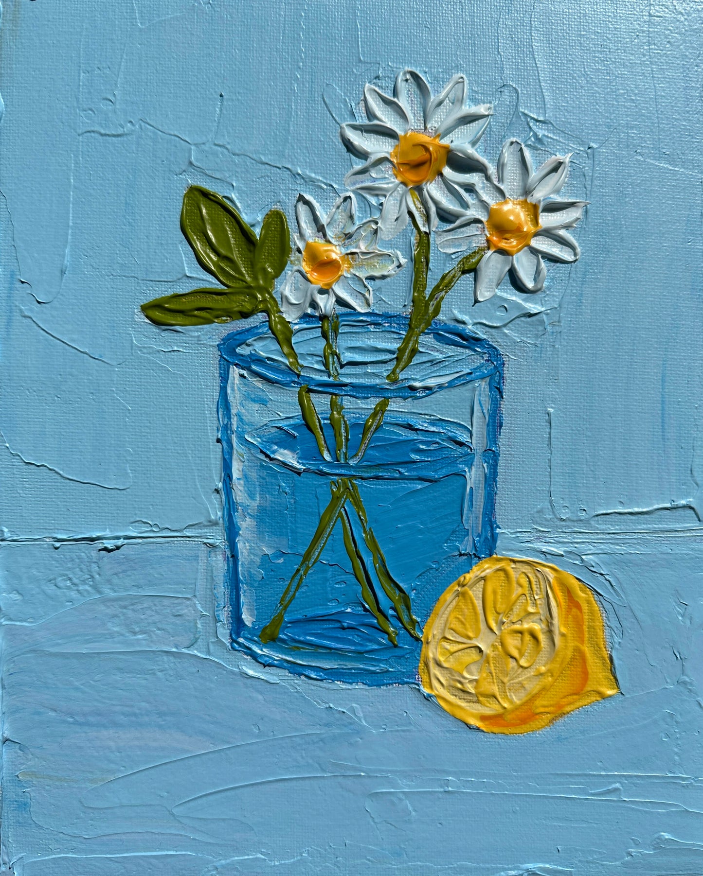 Painting of a glass jar with daisies and a lemon on a blue background