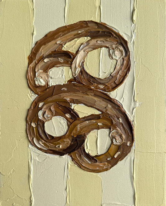Two chocolate pretzels on a textured beige background