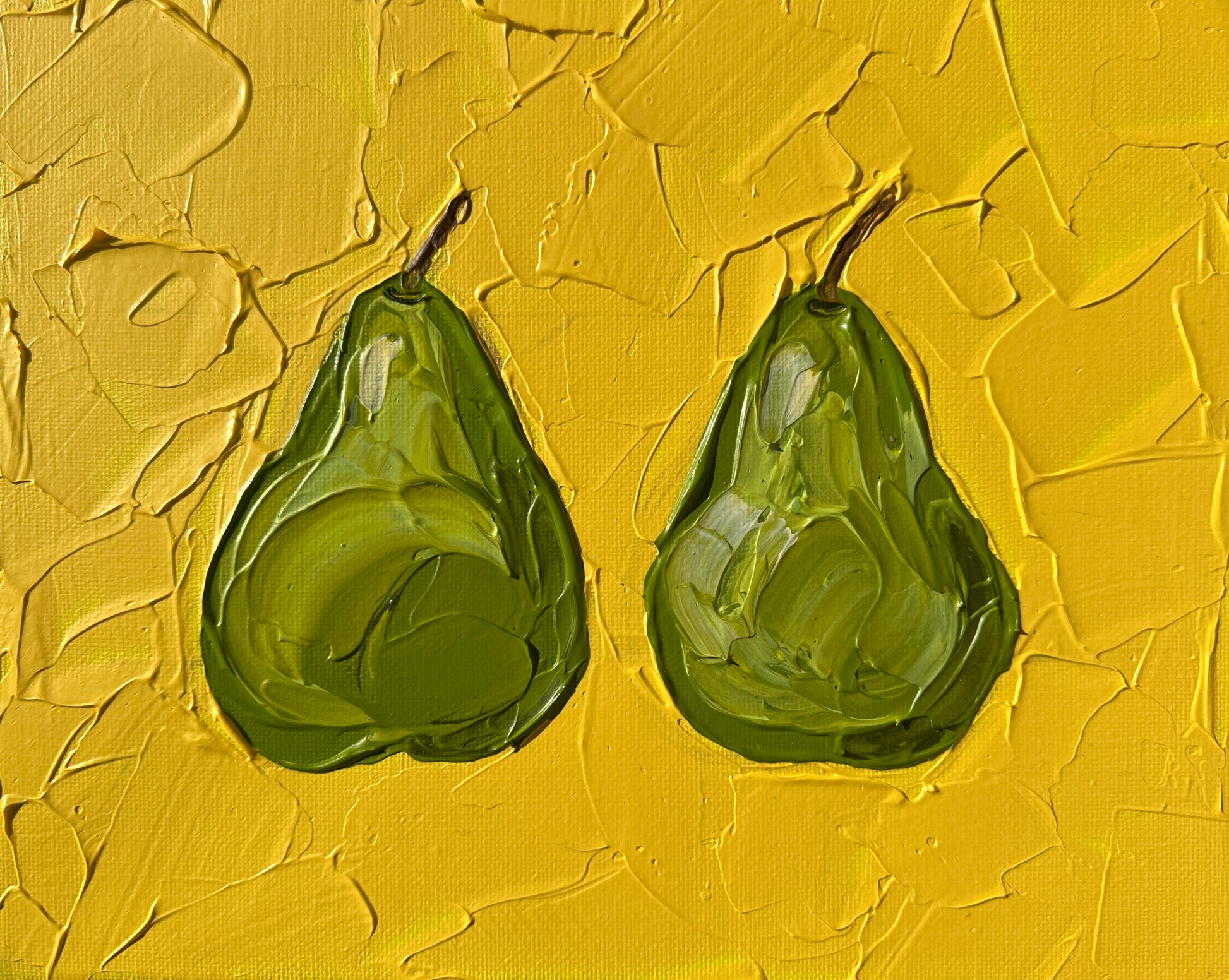 Two green pears on a textured yellow background